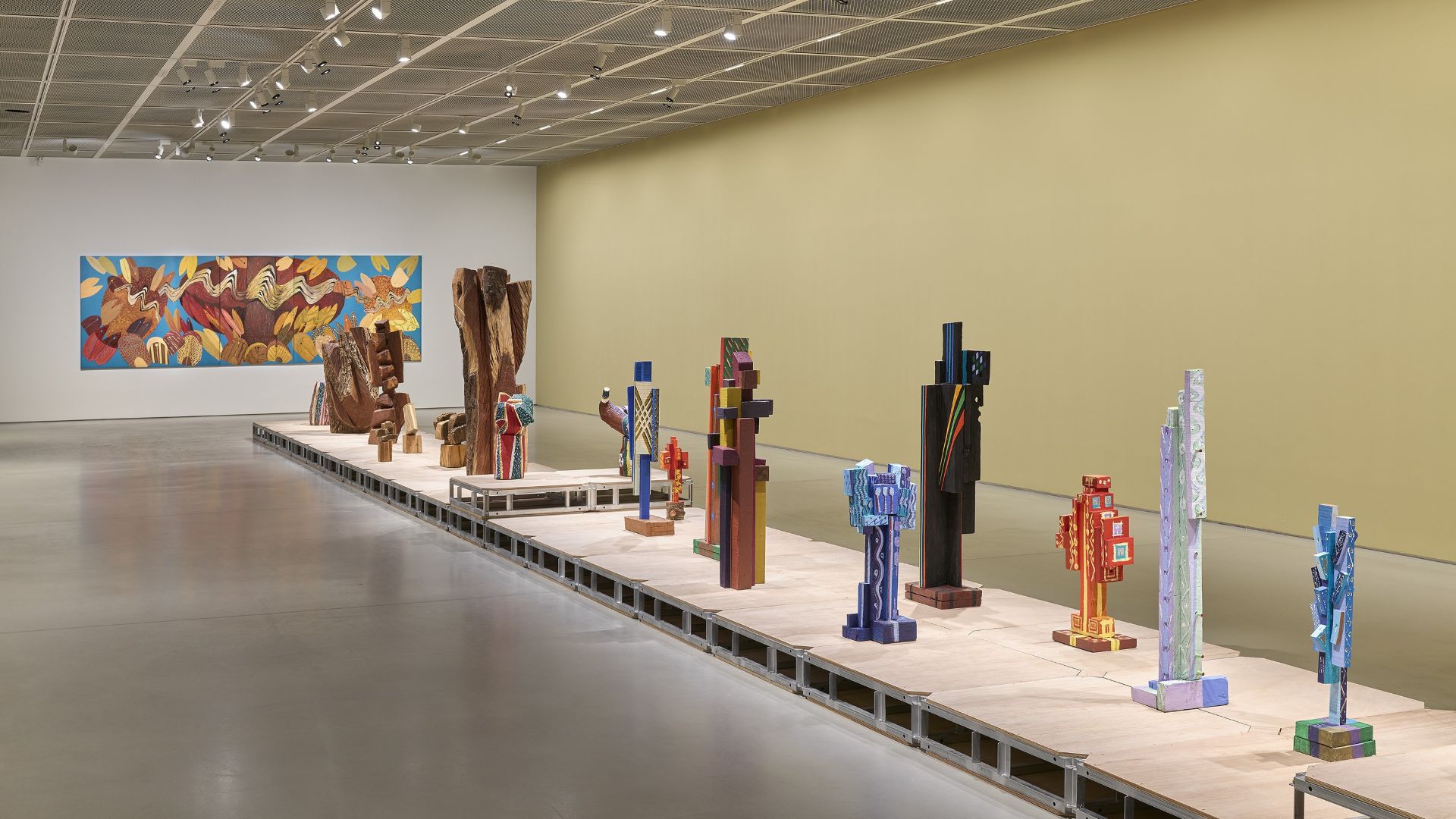 전시장 중앙 플랫폼 위에 다양한 색채의 조각 작품들이 설치된 전시 전경